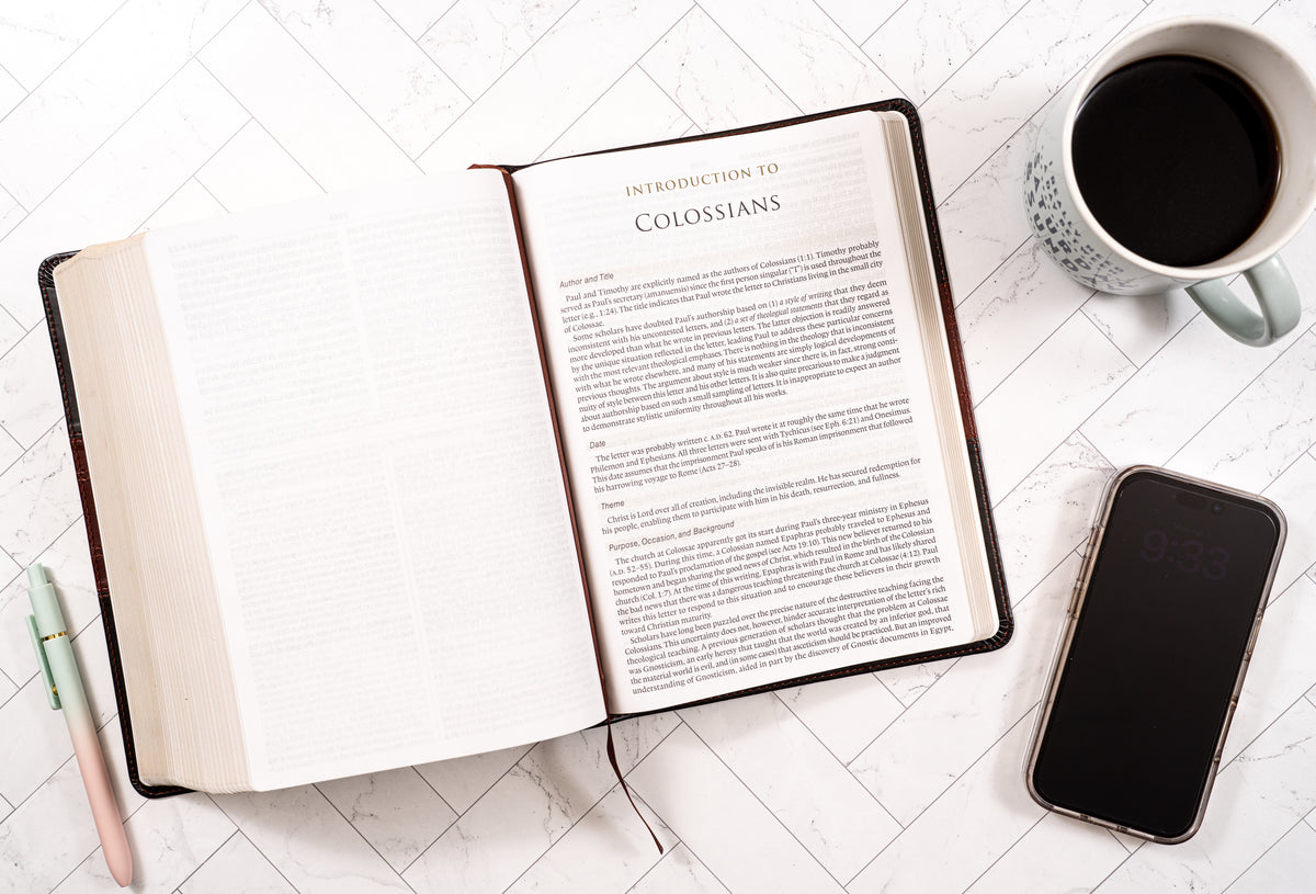 Open book on a table with a cup of coffee and smartphone
