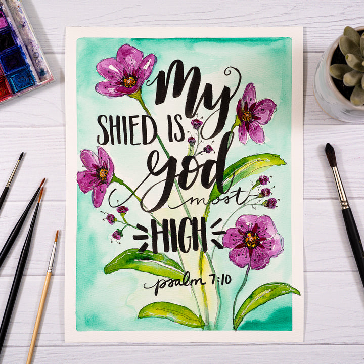 Art print with floral design and text on a white surface with art supplies.